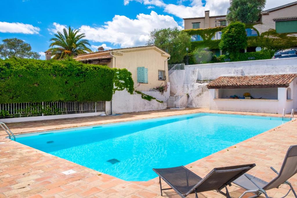 une piscine avec deux chaises et une maison dans l'établissement Bas de villa, piscine, 3 étoiles, à Saint-Paul-de-Vence