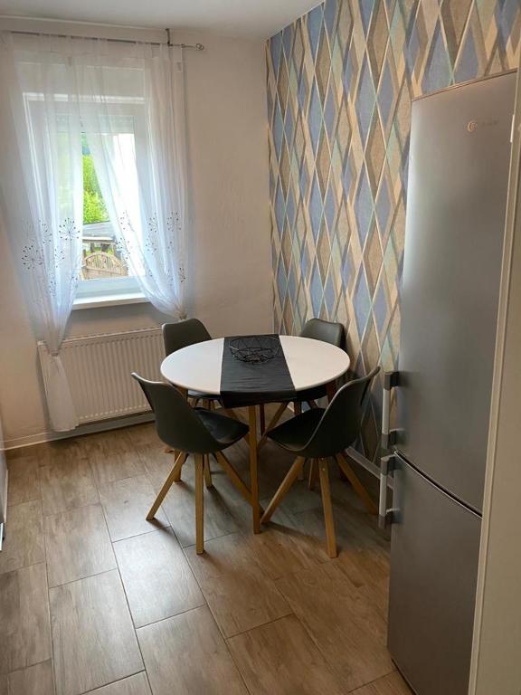 a kitchen with a table and chairs and a refrigerator at Ferienwohnung Da Emi in Neunkirchen