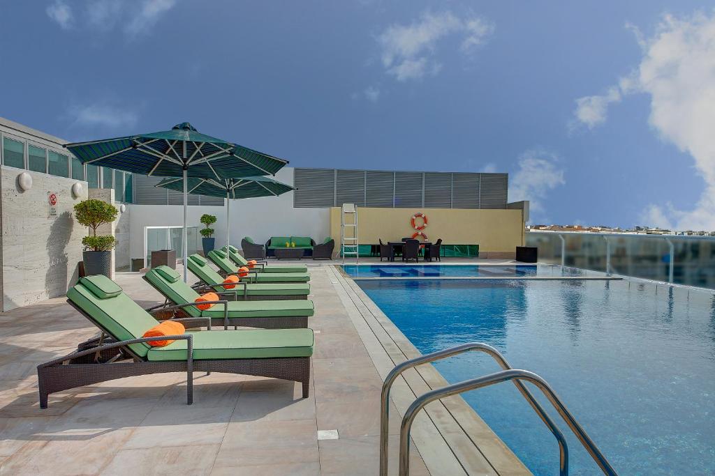 einen Pool mit Liegestühlen und einem Pool in der Unterkunft Al Khoory Atrium in Dubai