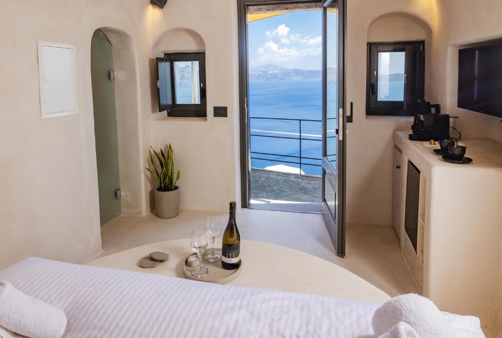 a bedroom with a bed with a bottle of wine at One of One - Aether in Oia