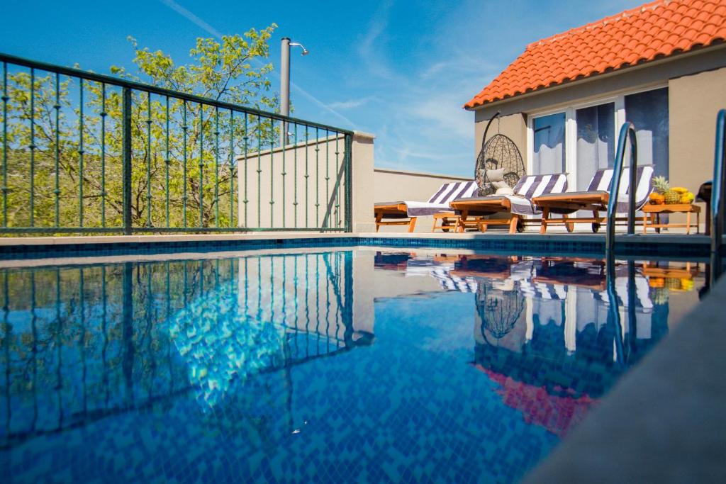 a swimming pool with chairs and a house at Holiday Home Moliva in Donje Sitno