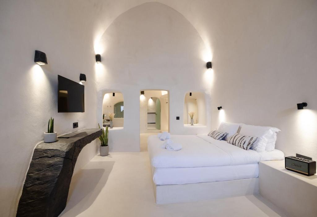a white room with a white couch and some mirrors at One of One - Aurelia in Oia