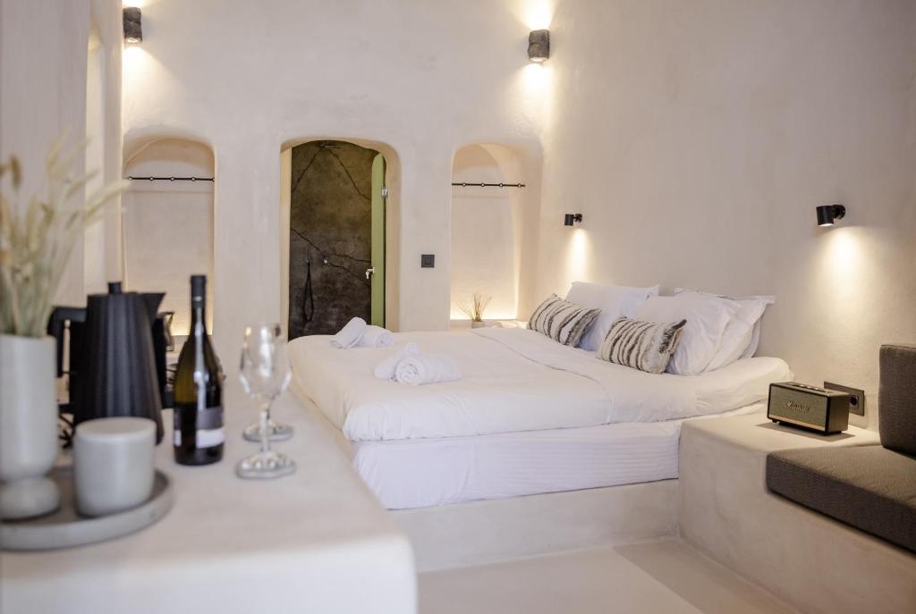 a white bedroom with a large white bed and a couch at One of One - Altheda in Oia