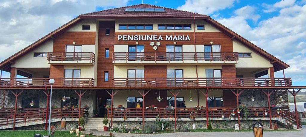 un gran edificio de madera con un cartel. en Pensiunea Maria, en Gilău