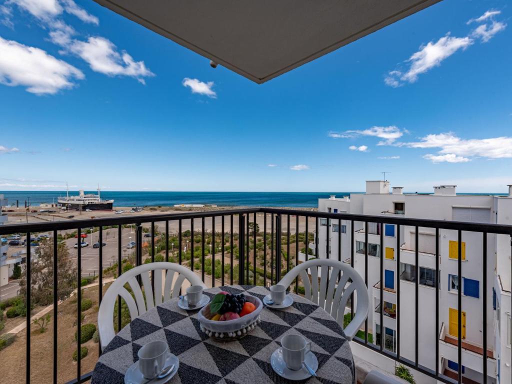a table with chairs on a balcony with a view of the ocean at Apartment Le Grand Pavois by Interhome in Le Barcarès