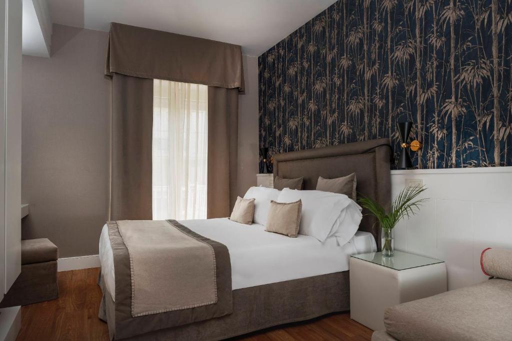 a bedroom with a bed and a wall with a floral wallpaper at Hotel Maestrale in Riccione