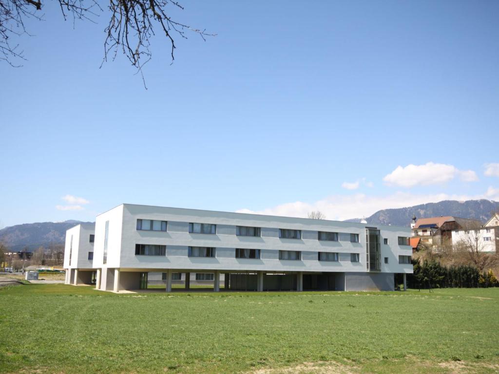 a large white building with a field in front of it at Apartment Techno-Park Villach by Interhome in Sankt Ulrich