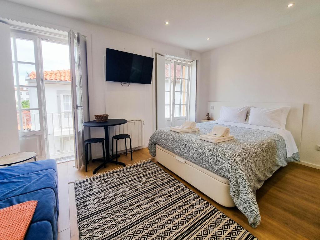 1 dormitorio con 1 cama y TV en la pared en SAM - Studio in the city center, en Viana do Castelo