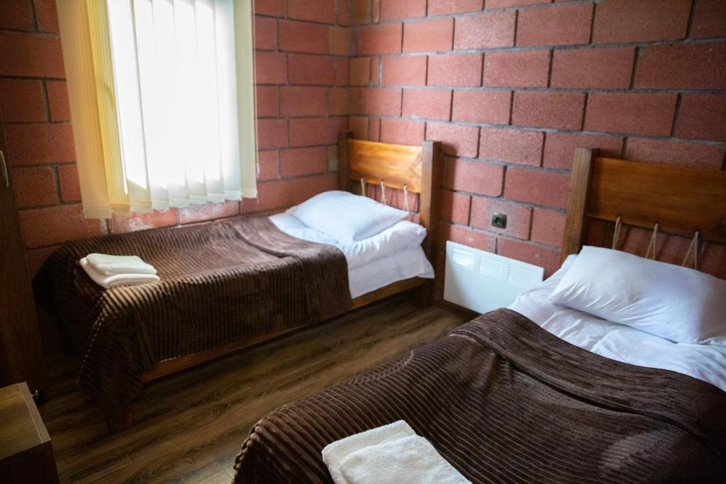 2 camas en una habitación con una pared de ladrillo en Noravank L-and-L, en Aghavnadzor