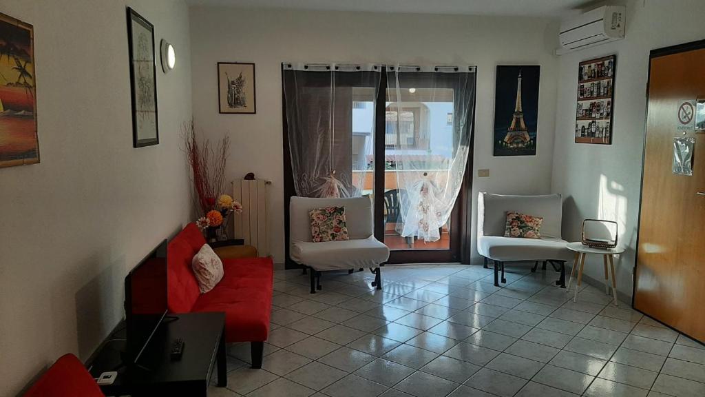 PRESSI AEROPORTO COSTA SMERALDA في أولبيا: غرفة معيشة مع أريكة حمراء وكرسيين
