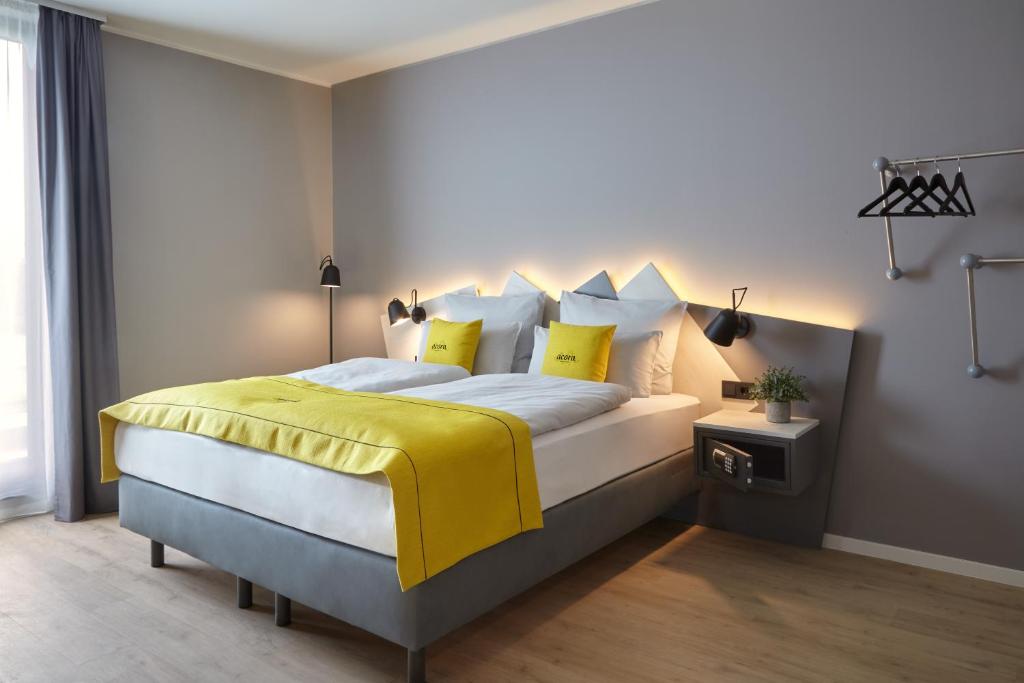 a bedroom with a large bed with yellow sheets and pillows at acora Düsseldorf Airport Living the City in Düsseldorf