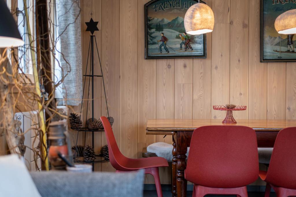 a dining room with a table and red chairs at Terre de Sapins in Orbey
