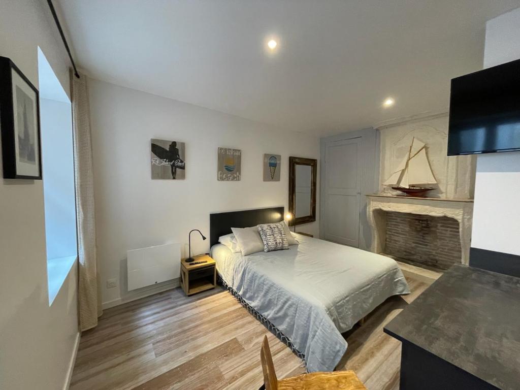 une chambre avec un lit et une cheminée dans l'établissement Le St Louis Chambre aménagée avec cuisine N°4, à La Rochelle