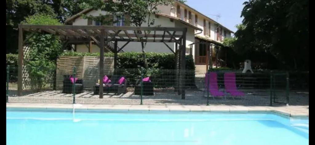 einen Pool mit lila Stühlen vor einem Haus in der Unterkunft Les Roseries Boutique Gite in Clussais-la-Pommeraie