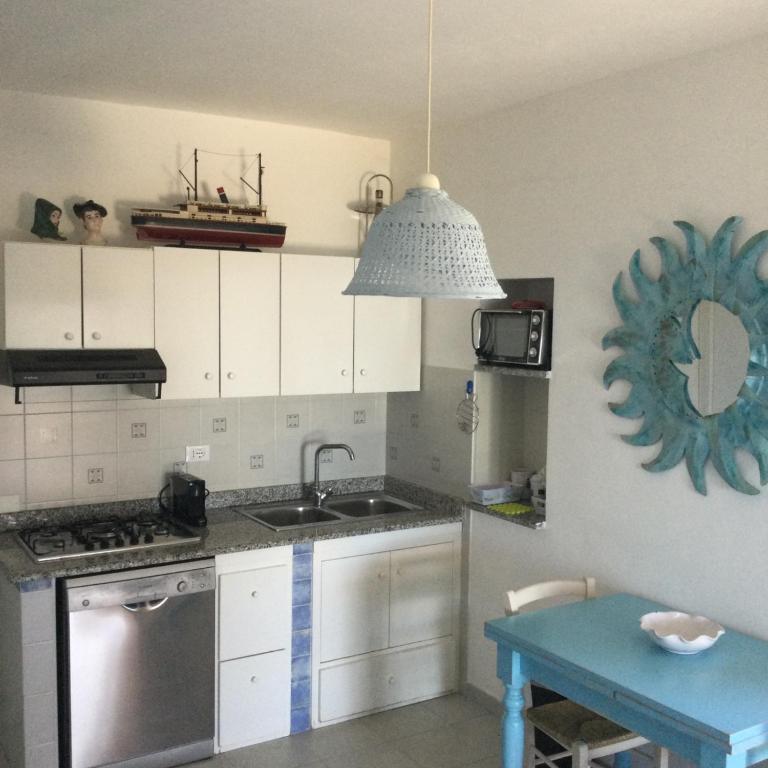 a kitchen with a sink and a stove and a table at Villa Vera trifamigliare con ingresso diretto 20 mt al mare clima wi-fi bbq in Cala Liberotto