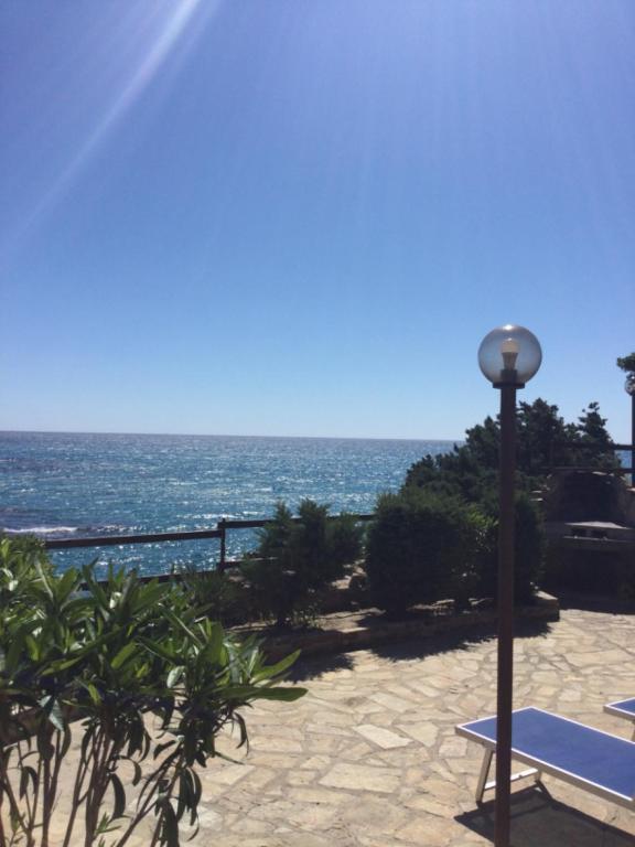 a view of the ocean with a bench and a lamp at Villa Vera trifamigliare con ingresso diretto 20 mt al mare clima wi-fi bbq in Cala Liberotto