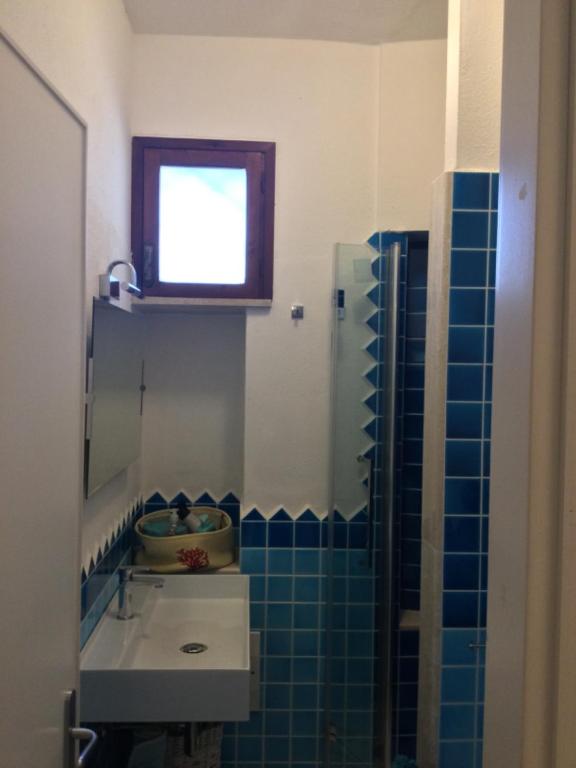 a bathroom with a sink and a window and blue tiles at Villa Vera trifamigliare con ingresso diretto 20 mt al mare clima wi-fi bbq in Cala Liberotto
