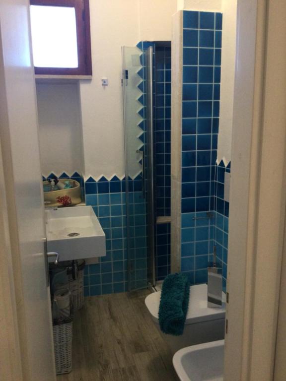 a blue tiled bathroom with a sink and a toilet at Villa Vera trifamigliare con ingresso diretto 20 mt al mare clima wi-fi bbq in Cala Liberotto
