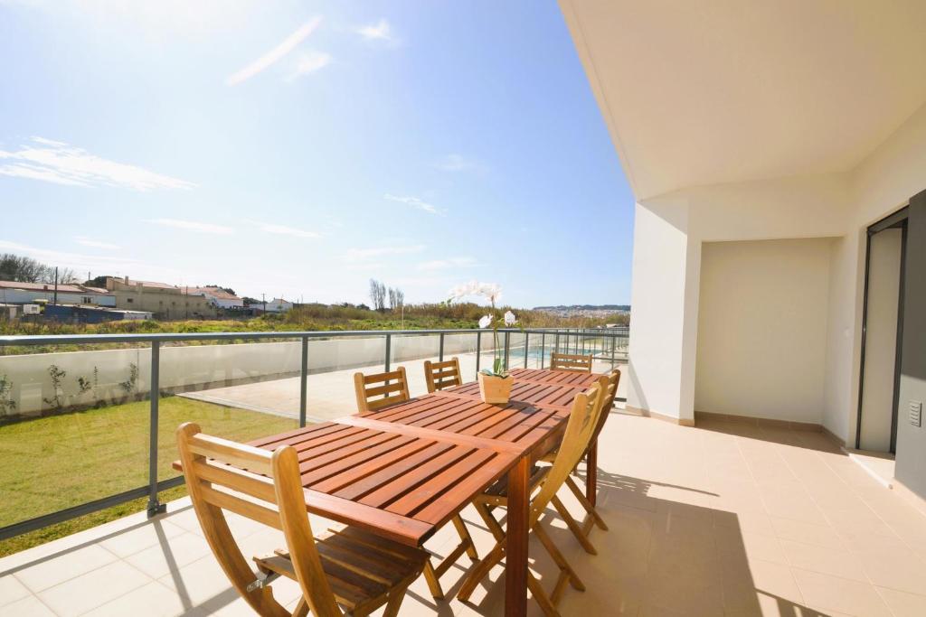 a wooden table and chairs on a balcony with a view at Mar T2 - By Smarthomes in São Martinho do Porto