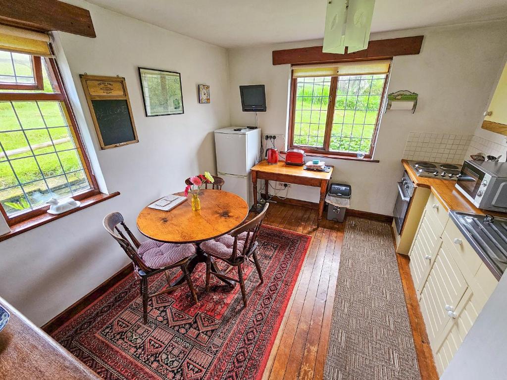 a kitchen with a table and chairs in a room at Wringford Farm Annexe in Cawsand