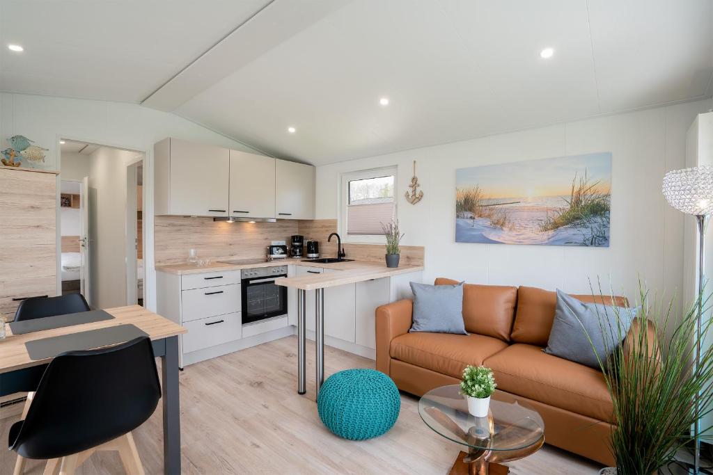 a living room with a couch and a kitchen at Ostseecamp Ferienhaus "Horizont" in Scharbeutz