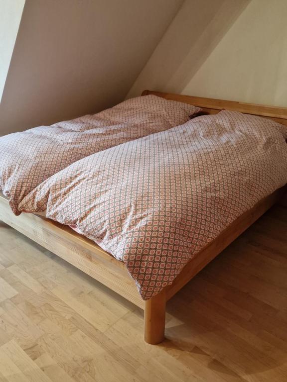 1 cama con marco de madera en el suelo de madera en Pension im Grünen 