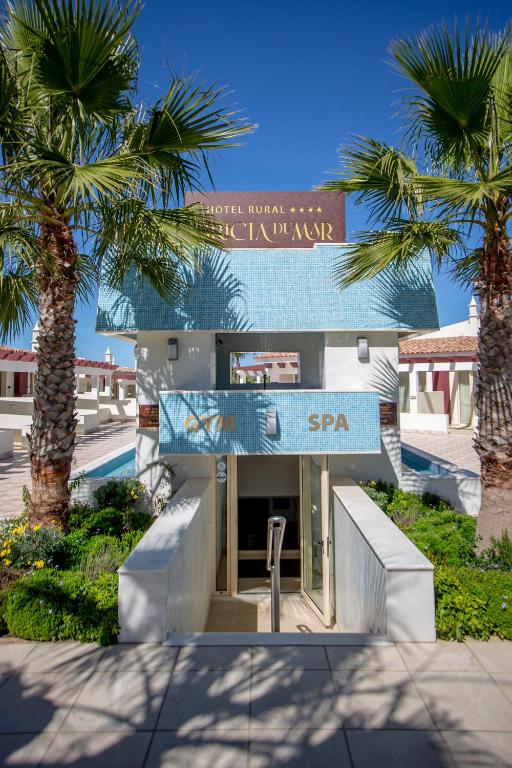 a building with palm trees in front of it at Hotel Rural Brícia Du Mar in Ferragudo