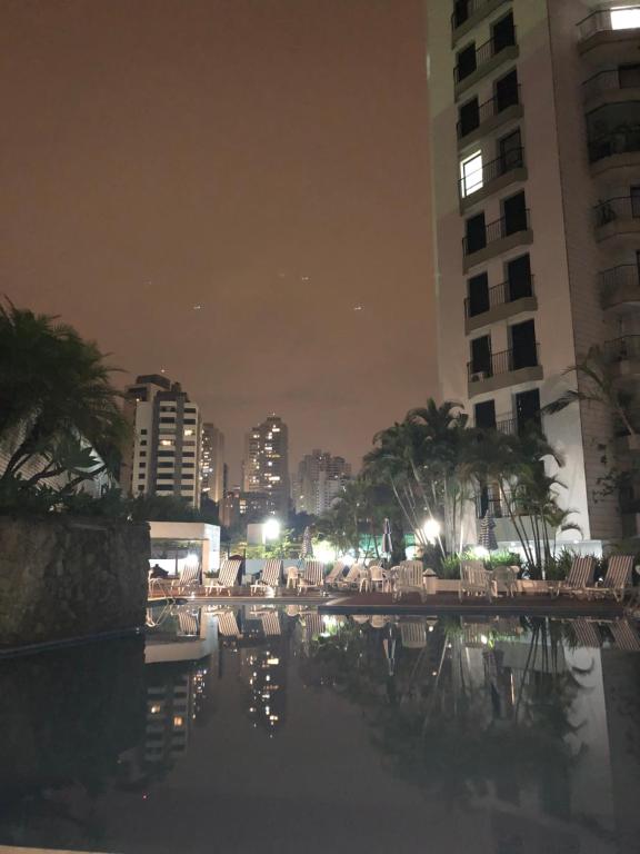 a pool with chairs and buildings at night at Allure Morumbi in Sao Paulo