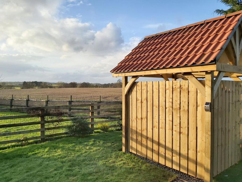 un cobertizo de madera con un techo oxidado junto a una valla en The Granary, en North Kilvington