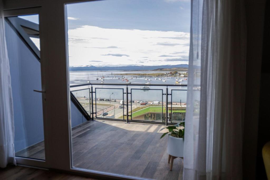 a room with a balcony with a view of the ocean at Gente del Sur - Cinco Hermanos in Ushuaia