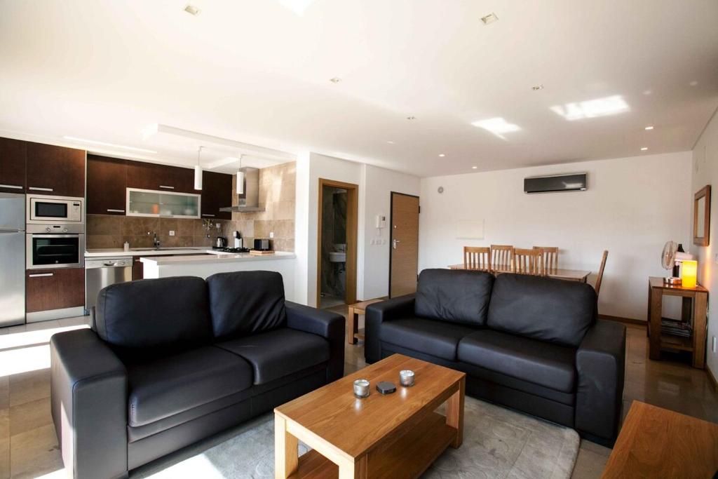 uma sala de estar com dois sofás pretos e uma mesa em Apartamento SUNSET T3 em São Martinho do Porto