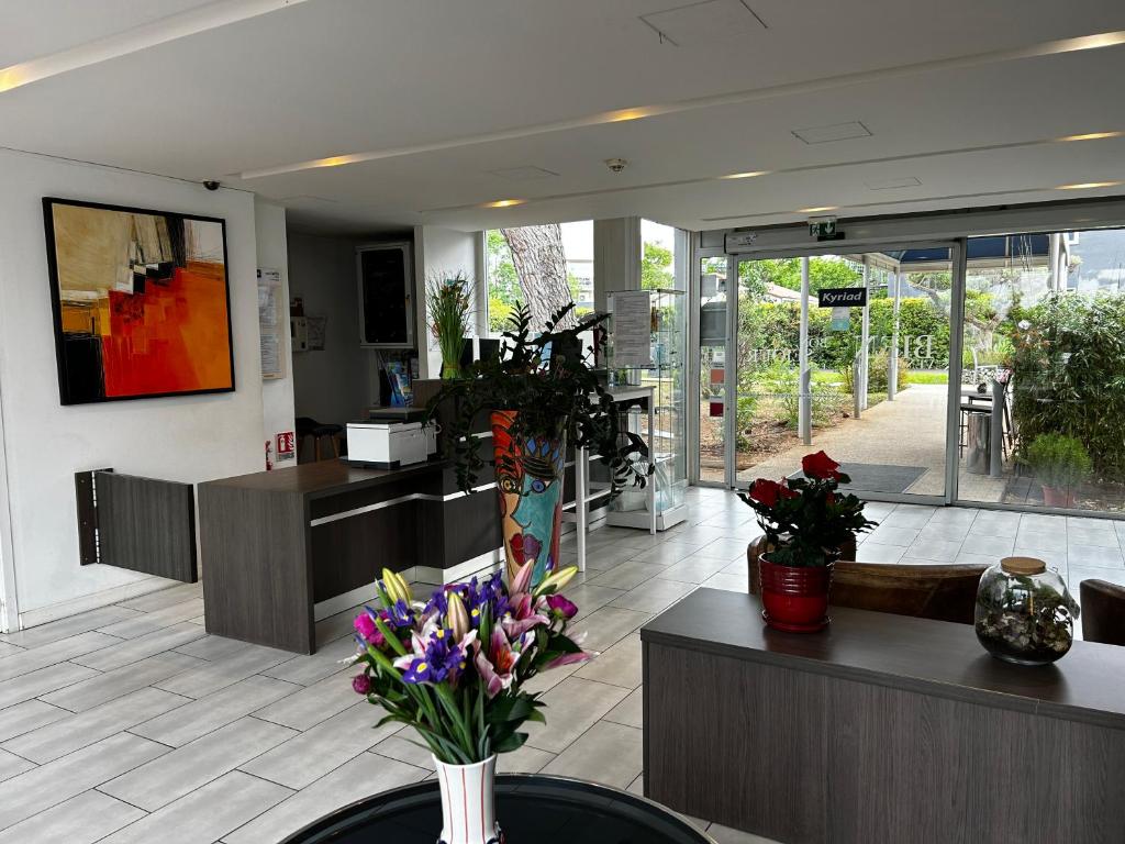 a lobby with flowers in a vase on a table at Kyriad Montpellier Aéroport - Parc Expo in Mauguio