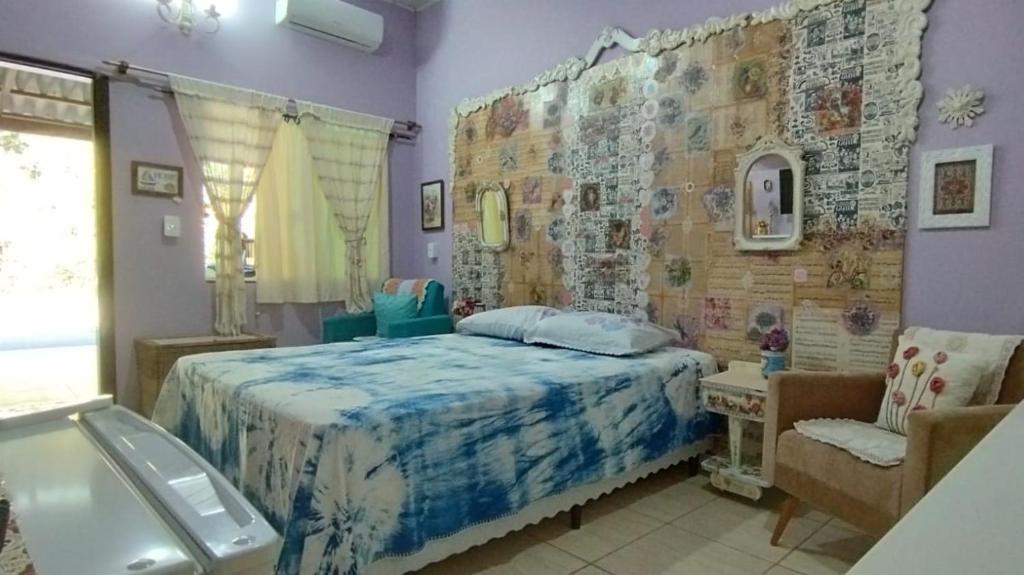 um quarto com uma cama grande e uma cadeira em Pernoites no Ateliê La Rosa II em Itapoá