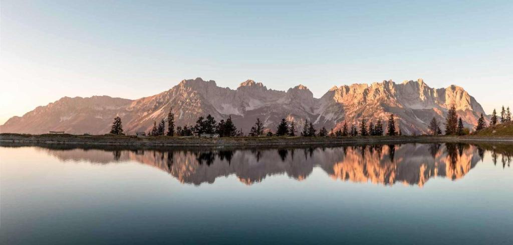 un reflejo de montaña en un lago con árboles y montañas en Going Living, en Going