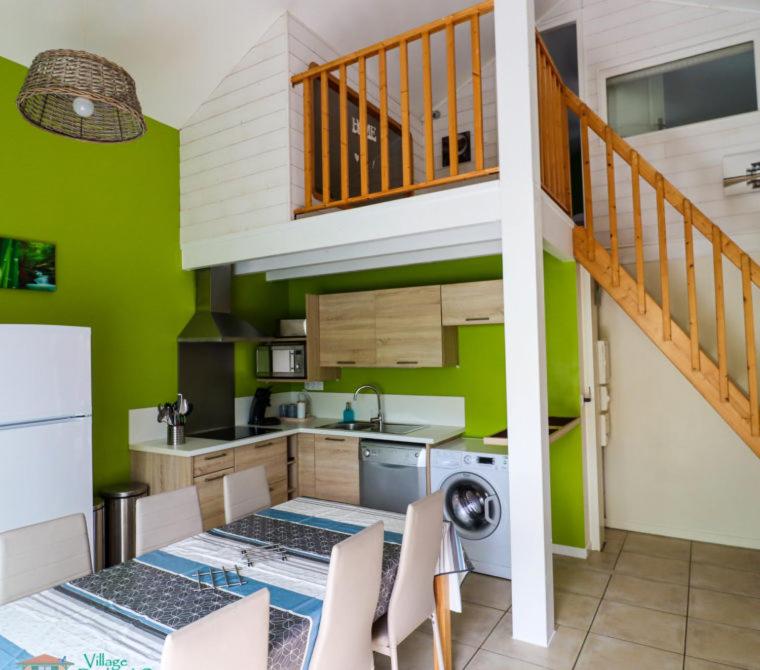 a kitchen with green walls and a table and a staircase at Village Drôles d&#39;Oiseaux in Le Teich