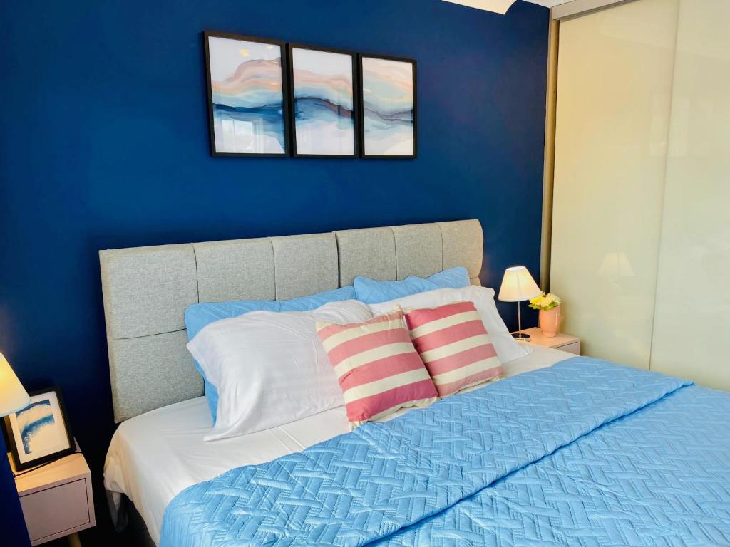 a blue bedroom with a bed with two pillows at Cloud9StayZ at The Leafield in Woking