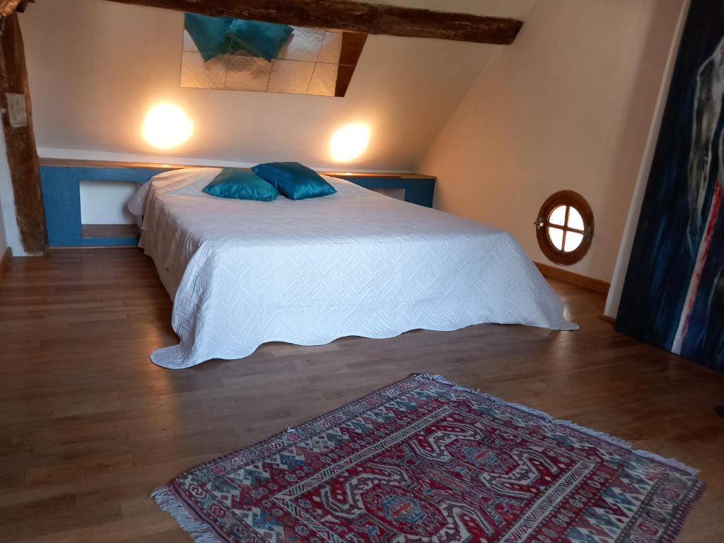 - une chambre avec un lit doté d'oreillers bleus et d'un tapis dans l'établissement Moulin en bord de rivière - 1 à 5 pers - logement atypique-linge-wifi, à Chevillon-sur-Huillard