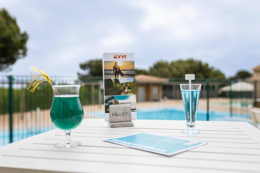 a table with two glasses and a book on it at VVF Narbonne-Plage Saint-Pierre-la-Mer in Fleury