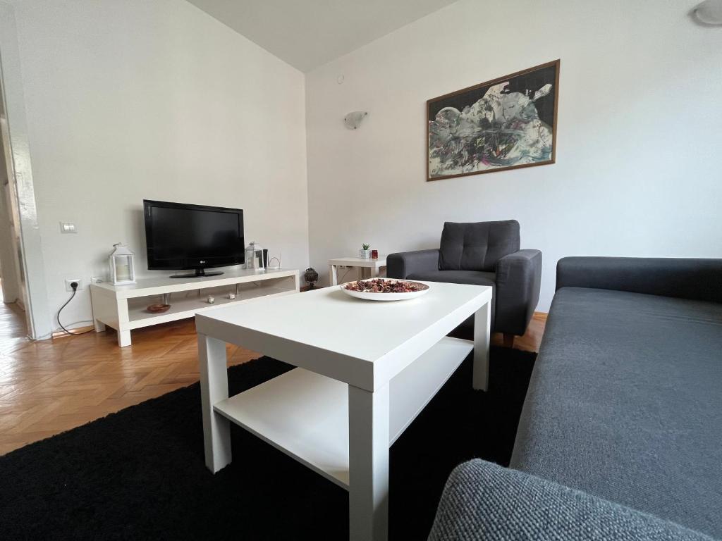 a living room with a white table and a tv at Mickitos Square Apartment in Skopje