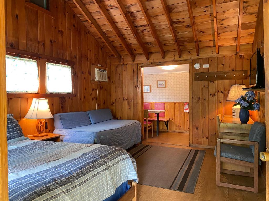 a bedroom with two beds in a wooden cabin at Amber Lantern Efficiency Cottage in Lake George