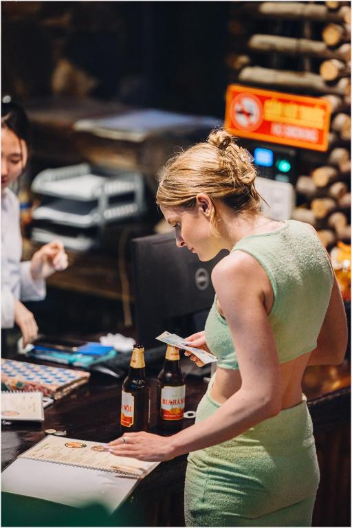 a woman standing at a counter with bottles of beer at Trang An Ecolodge in Ninh Binh