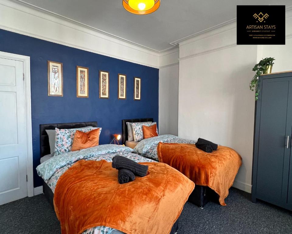 1 dormitorio con 2 camas con sábanas de color naranja en Vintage Vibes By Artisan Stays in Southend-On-Sea I Free Parking I Weekly or Monthly Stay Offer I Sleeps 5 en Southend-on-Sea