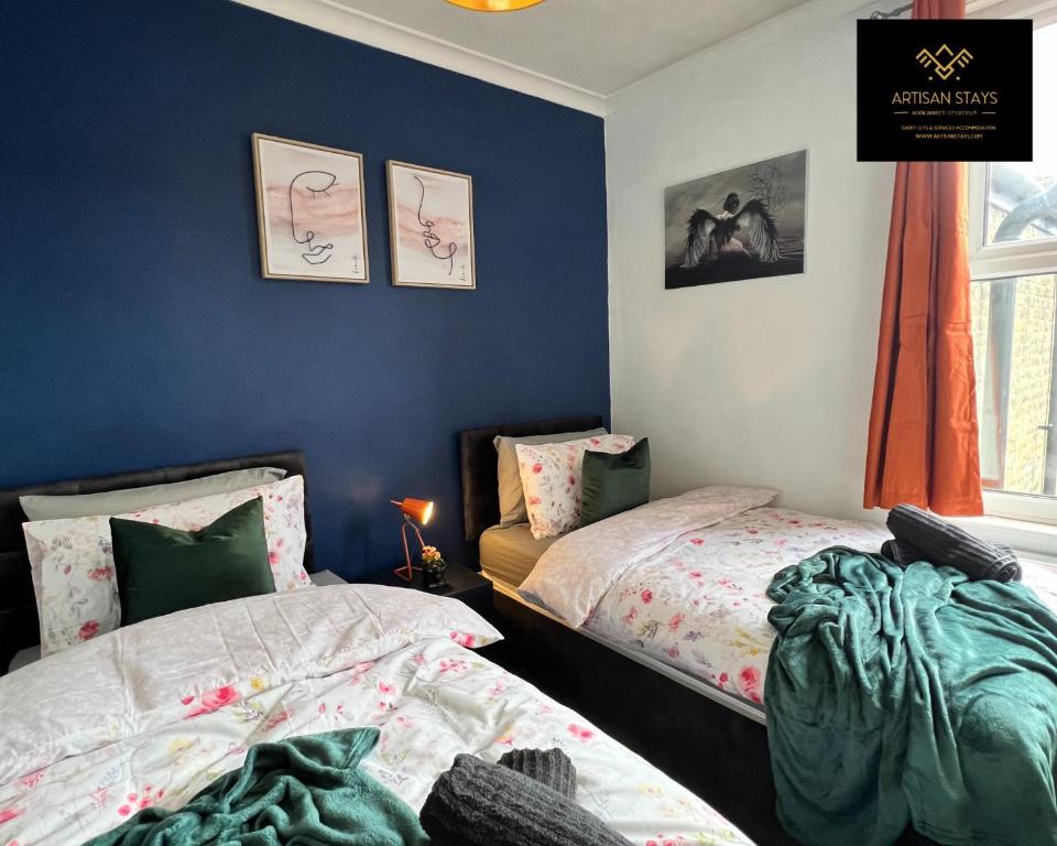 a bedroom with two beds and a blue wall at Vintage Vibes By Artisan Stays in Southend-On-Sea I Free Parking I Sleeps 5 in Southend-on-Sea