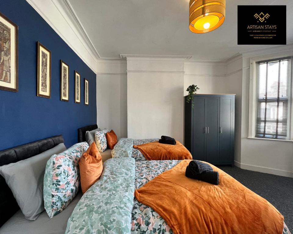2 camas en una habitación con paredes azules en Vintage Vibes By Artisan Stays in Southend-On-Sea I Free Parking I Contractors & Families I Sleeps 5, en Southend-on-Sea