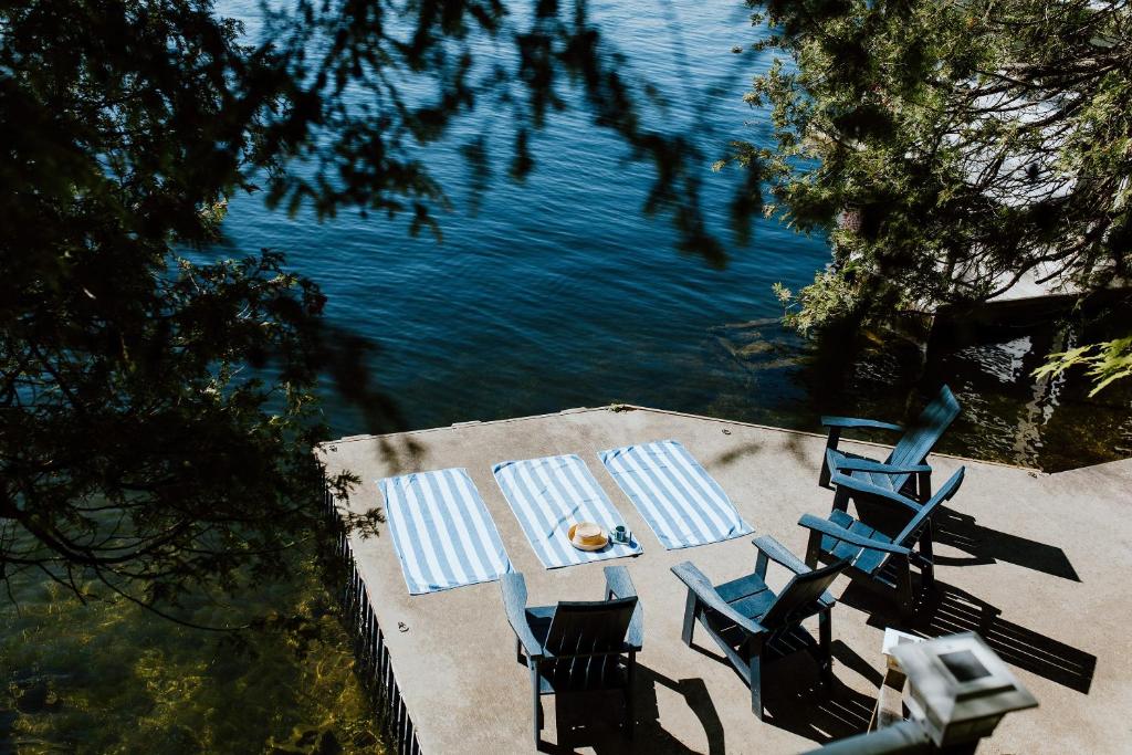 a table and chairs sitting next to the water at The Dance Hall Cottage on Charleston Lake in Delta