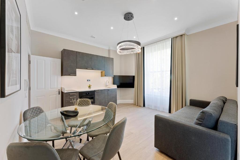 un salon avec une table en verre et des chaises dans l'établissement Cleveland Residences Paddington, à Londres