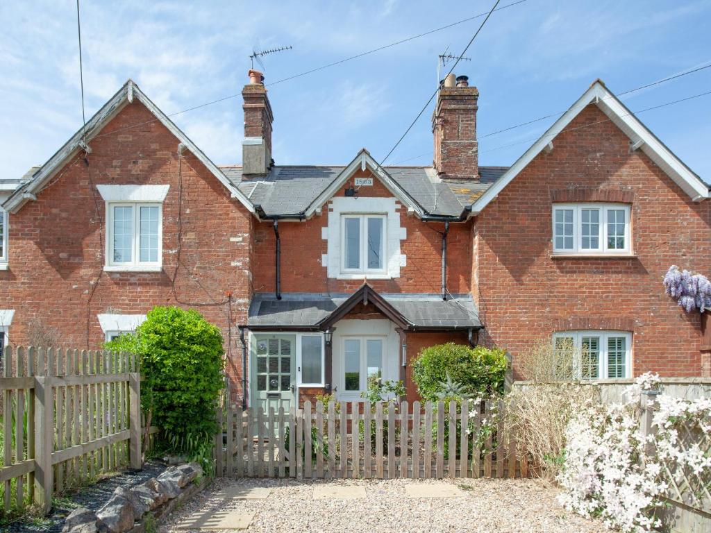 una casa de ladrillo rojo con una valla de madera en Meadow Pit Cottage en Topsham