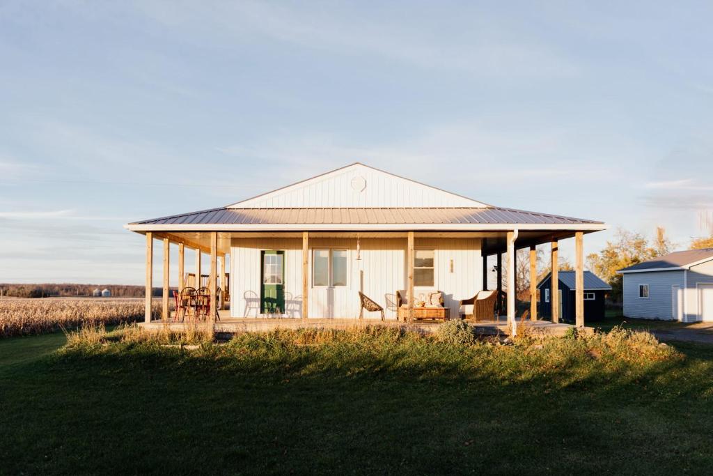 ein weißes Haus mit einer Veranda mit Stühlen darauf in der Unterkunft Fox Lane - Prince Edward County Farmhouse in Picton