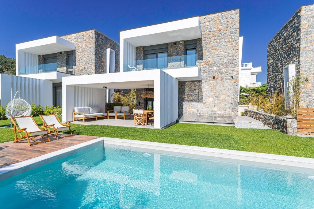 a villa with a swimming pool in front of a house at Apoikia Villas Pefkochori in Pefkohori