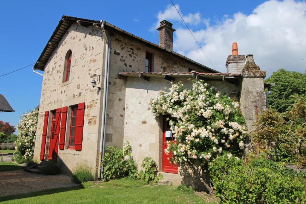 an old stone house with red doors and flowers at Le jardin in Saint-Priest-Taurion